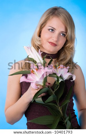The attractive woman with a bouquet of lilies isolated on a dark blue background.