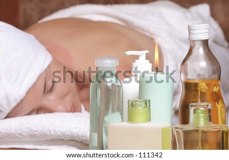 Woman on massage table with oils, essential oils, candles, scents.  Focus on products.
