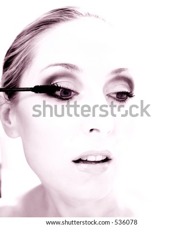 Woman putting on mascara - photo has been toned and  softness added for effect. This image could be used for beauty or could also be an actress or theatrical entertainer.