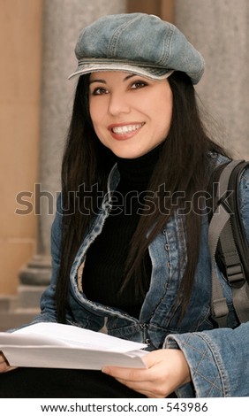 Uni student holding papers and smiling.