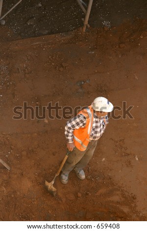A workman leans on his shovel in a dirt pit