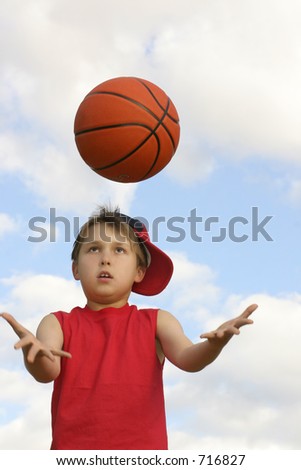 Boy in a red tank top catching a ball.  Shot against a cloudy sky, afternoon  Focus on face and ball, hands in motion 200 iso
