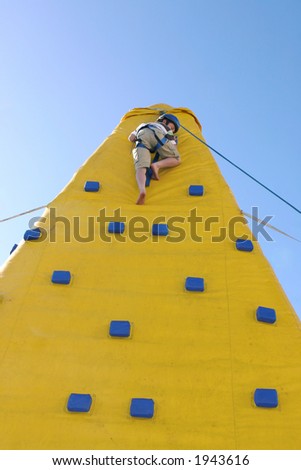 A boy makes the journey down from the top of a climbing wall.