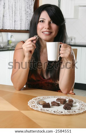 A beautiful woman enjoys coffee and chocolates.