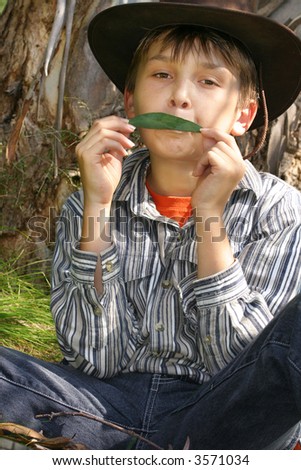 Green Eco-Music - A boy holds a simple gum leaf against the lips and blown. A gumleaf is capable of complex and highly expressive music. It has been mistaken for a whistle, flute, clarinet, saxophone.