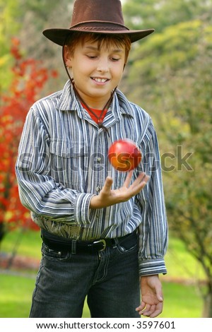 Nature\'s best. A boy standing in fresh pristine country,  is throwing up an organic grown red apple. eg:  green living, healthy lifestyle, organic produce.  Note: motion in apple and hand, 400iso