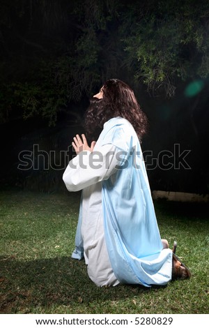 Side view of Jesus in Garden of Gethsemane on knees praying to God.