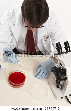 Scientist, biologist or other laboratory research worker prepares a glass slide for viewing under the microscope.
