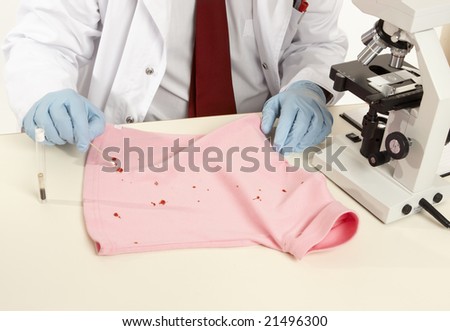 Closeup of a forensic expert swabbing and analysing a stain from a shirt.