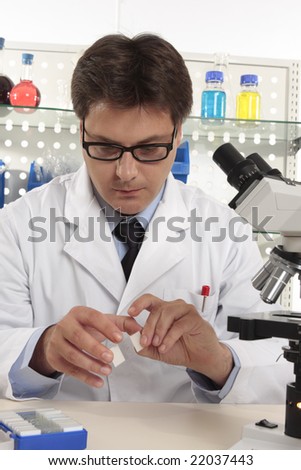 Scientist sitting at desk in a a laboratory using microscope slides