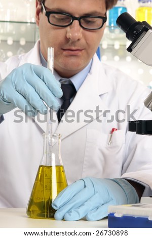 Scientist using a stirrer to mix liquids in flask.  Focus to hands and science labware.