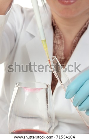A forensic investigator or criminologist uses a pipette to take a sample of the contents inside a glass for analysis.  Focus to pipette.