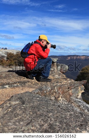 A photographer or traveller shoots photos of a scenic mountain landscape.