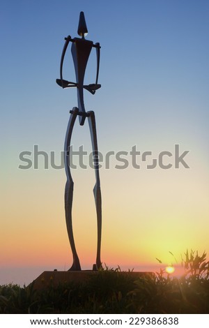 BONDI, AUSTRALIA -  NOVEMBER 9, 2014; Sculpture by the Sea 2014.  The sun rises on the horizon behind sculpture titled Big Man  by Will Maquire, NSW  Made of hot forged steel.   Note ISO 8000 used