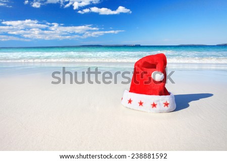 Santa red hat on a beautiful beach in summer.  Christmas downunder, Christmas or holiday vacation.  Shallow dof used with focus only to the fluffy red and white hat