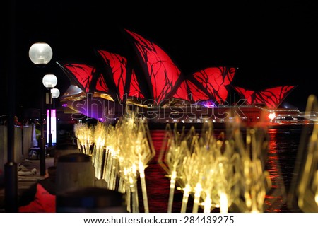 SYDNEY, AUSTRALIA - MAY 27, 2015;  The Sydney Opera House in vivid red .  In the foreground another exhibit entitled Tidal Reed Garden leads the viewers eye along the wharf towards the Opera House.