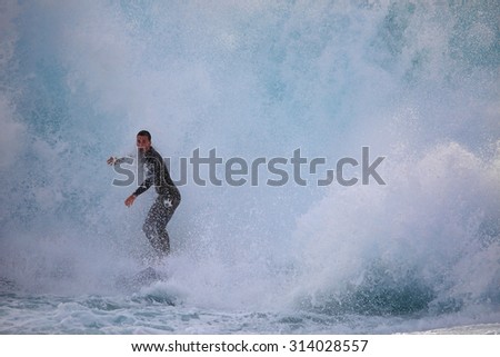 CAPE SOLANDER, AUSTRALIA - AUGUST 27, 2015; Surfer riding through a massive wave as it crashes around him at Cape Solander