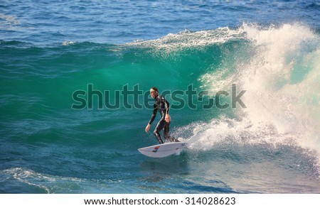 CAPE SOLANDER, AUSTRALIA, AUGUST 9, 2015; a male surfer, catching and surfing the breaks off Cape Solander near Sydney on a beautiful and sunny winter day.