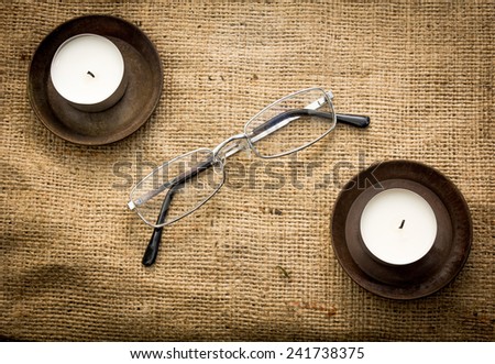 Two candles and reading glasses on a cloth