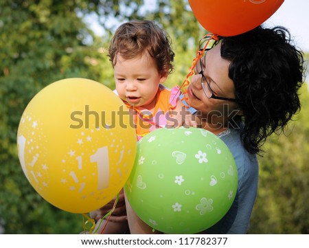 Birthday party for one year old baby girl. Mother is holding baby in her arms.