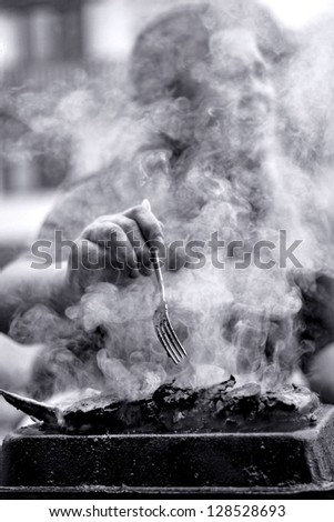 A woman behind the smoke from the barbecue