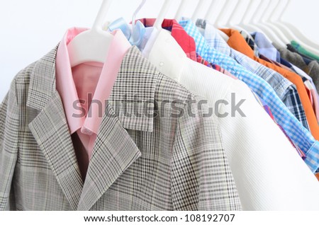 some shirts and jackets arranged on clothes hanger