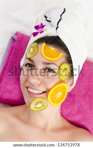 Attractive young woman getting a fruits facial mask in the beauty spa