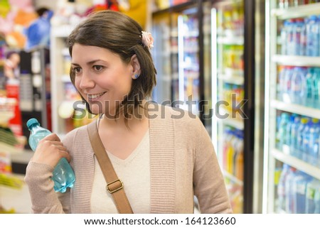 Young woman buying a bottle of water from a store
