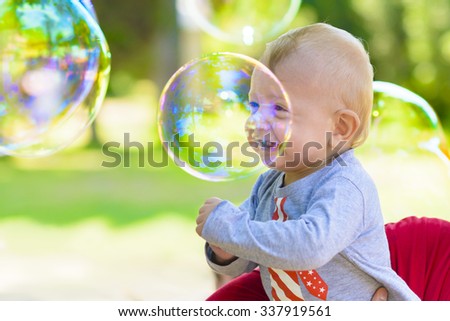 Cute baby catching soap bubbles in a summer day