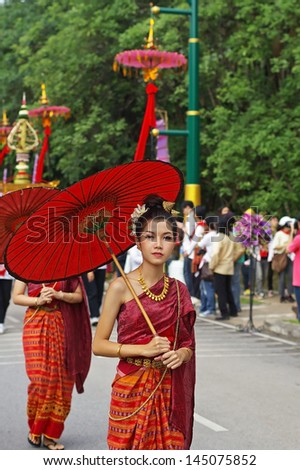CHIANG MAI, THAILAND - JULY 7: young girl student in Chiang Mai University wear the Thailand local costume with red umbrella in Doi Suthep Temple respect day on 6 July 2013 in Chiang Mai, Thailand