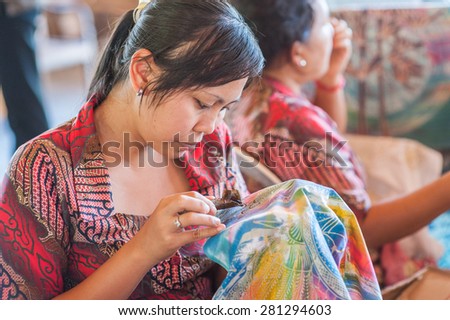 BALI, INDONESIA - NOVEMBER 3RD 2015 : Balinese woman use chanting and wax to make Batik. Batik-making is part of Indonesian culture and tourist attraction in Bali, Indonesia.