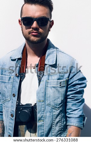 Closeup of young hipster man with camera outdoors.