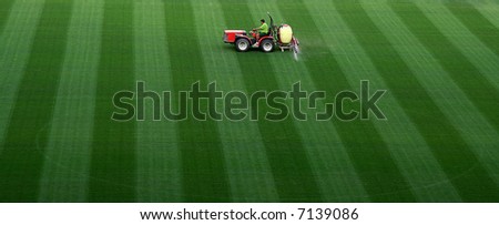 Sports field watering by man seating on a tractor at Camp Nou stadium in Barcelona.