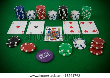 Poker set with chips and cards on the green table - small blind chip.