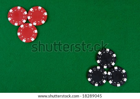 Two kinds of poker chips in two corners of a green poker table. Top view.