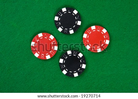 Two kinds of poker chips in the middle of green poker table. Top view.