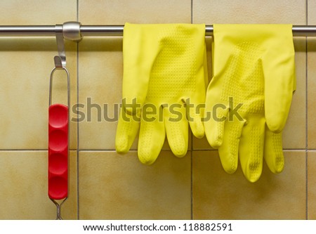 Rubber Gloves and Red Handled Tool Against Kitchen\'s Wall