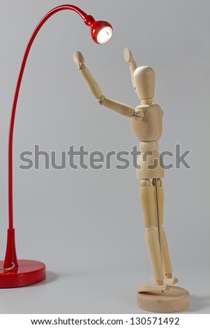 Wooden Mannequin Under the Beam of a Red Reading Lamp