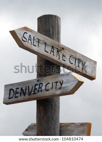 Humorous weathered signs pointing toward Denver and Salt Lake City