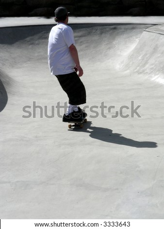 Skate boarder taking an easy ride through the bowl