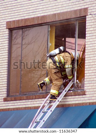 Fire fighter entering smoldering room through a broken window