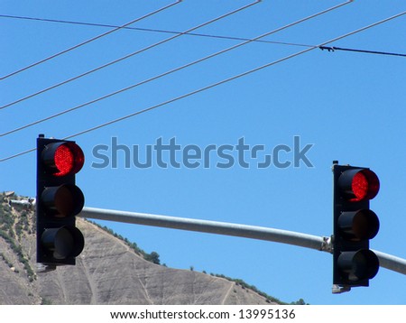 Dual stop lights amid power lines and deep blue sky