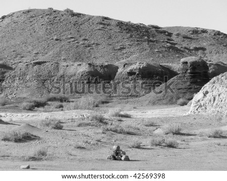 Heap of stones in the midst of the vast desert badlands of the New Mexico desert - black and white photograph