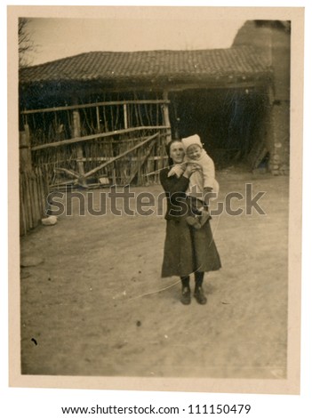 CENTRAL BULGARIA, BULGARIA,- CIRCA 1950 : the area Karlovo - child in the arms of his grandmother, a village backyard - circa 1950