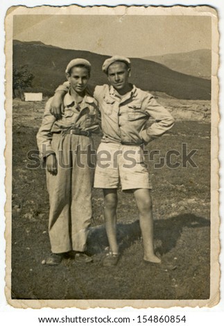 CENTRAL BULGARIA, BULGARIA - CIRCA 1945: Two friends holding arms (in the mountainous countryside) - Note: slight blurriness, better at smaller sizes - circa 1945