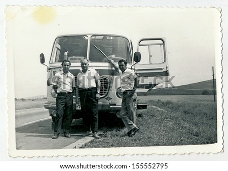 CENTRAL BULGARIA, BULGARIA - CIRCA 1960: Three middle aged men standing in front of the bus, on the road - Note: slight blurriness, better at smaller sizes - circa 1960