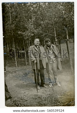 CENTRAL BULGARIA, BULGARIA, district Plovdiv - CIRCA 1975: Two men of different ages (older leans on a stick) in forest  circa 1975