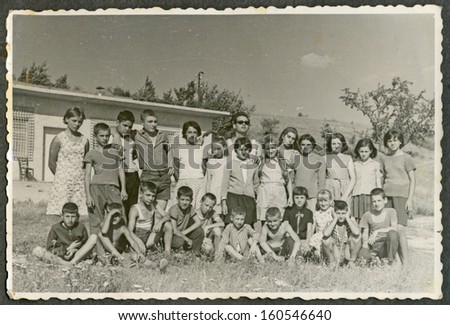 CENTRAL BULGARIA, BULGARIA - CIRCA 1970 - A group of children with the teacher at a summer camp (posing in front of building) circa 1970
