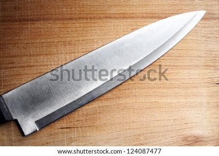 Sharp steel kitchen knife for cooking on old cut vintage kitchen board close up