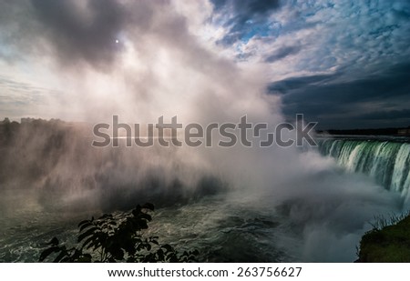 The sun shines through heavy wet mist as it rises out of the mighty Niagara river Falls